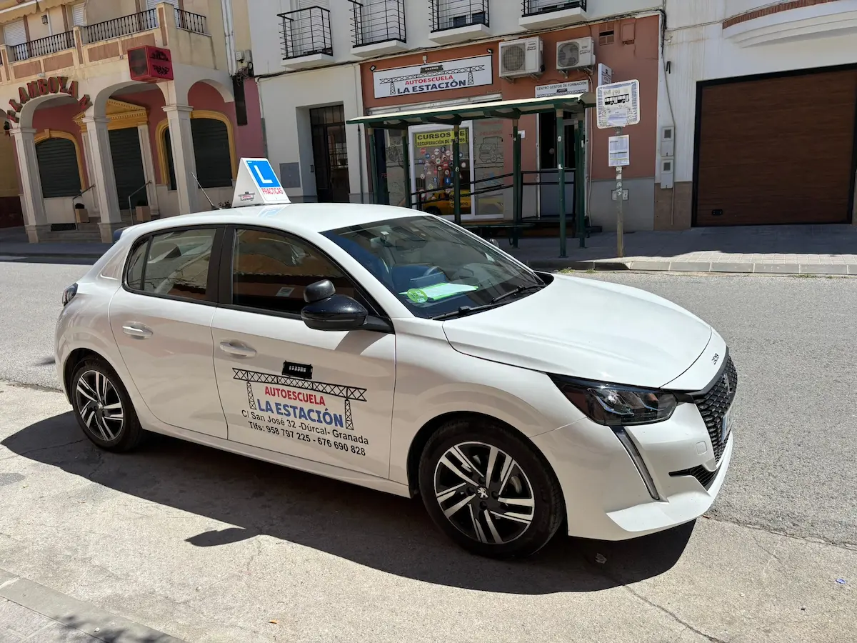 Imagen de fachada de la autoescuela al fondo con un coche de la escuela en primer plano